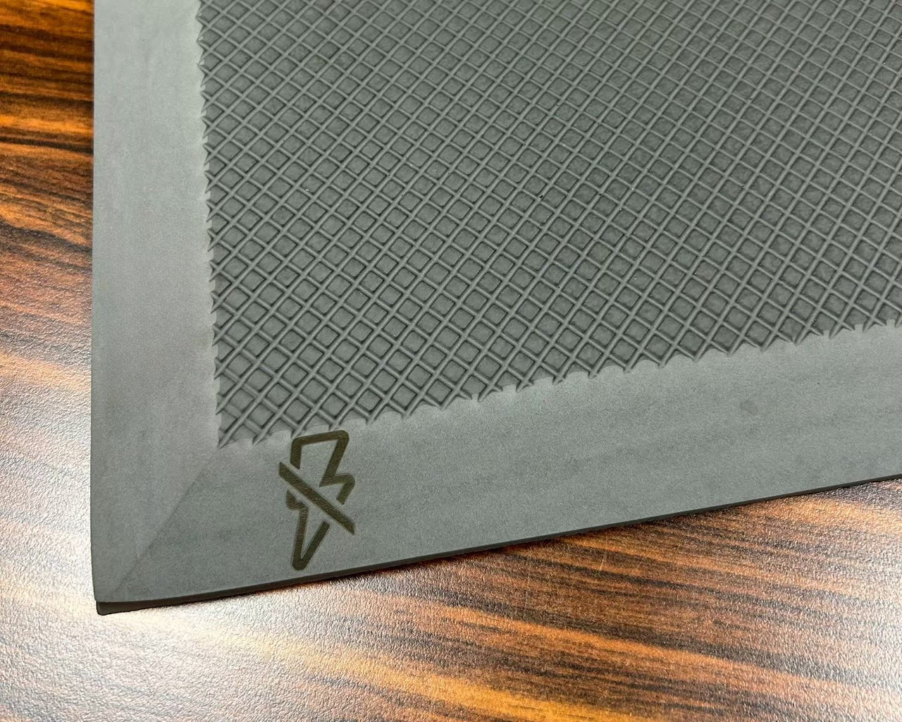 Corner close-up of an anti-static commercial anti-fatigue mat with a laser-engraved conductive warning icon
