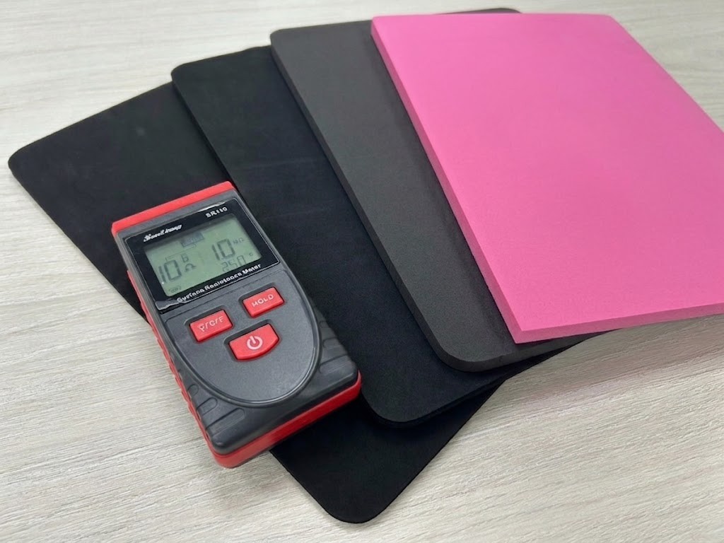 Black and pink anti-static foam sheets being tested for surface resistivity with a handheld surface resistance meter