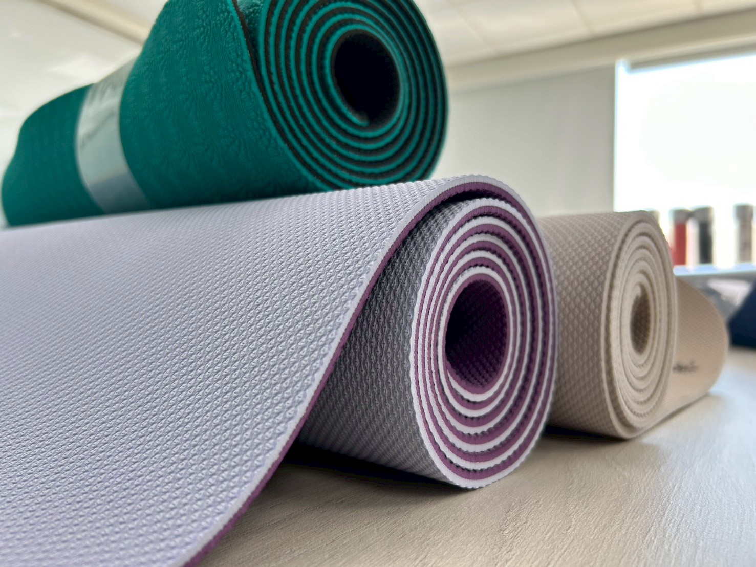 Rolled dual-layer TPE yoga mats showing diamond surface texture and contrasting underside colors