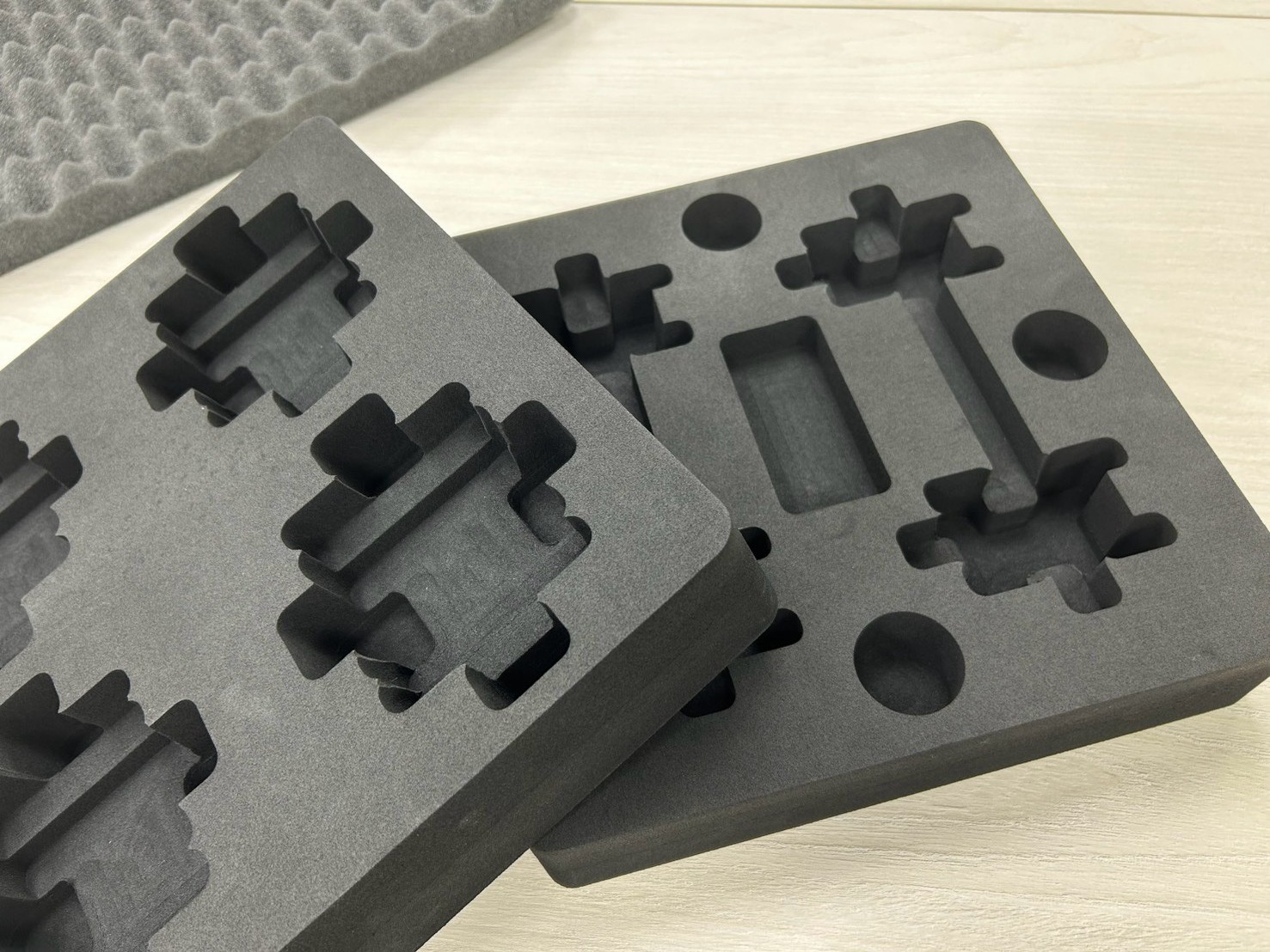 Black CNC-milled anti-static foam trays with custom pocket shapes for electronic component packaging